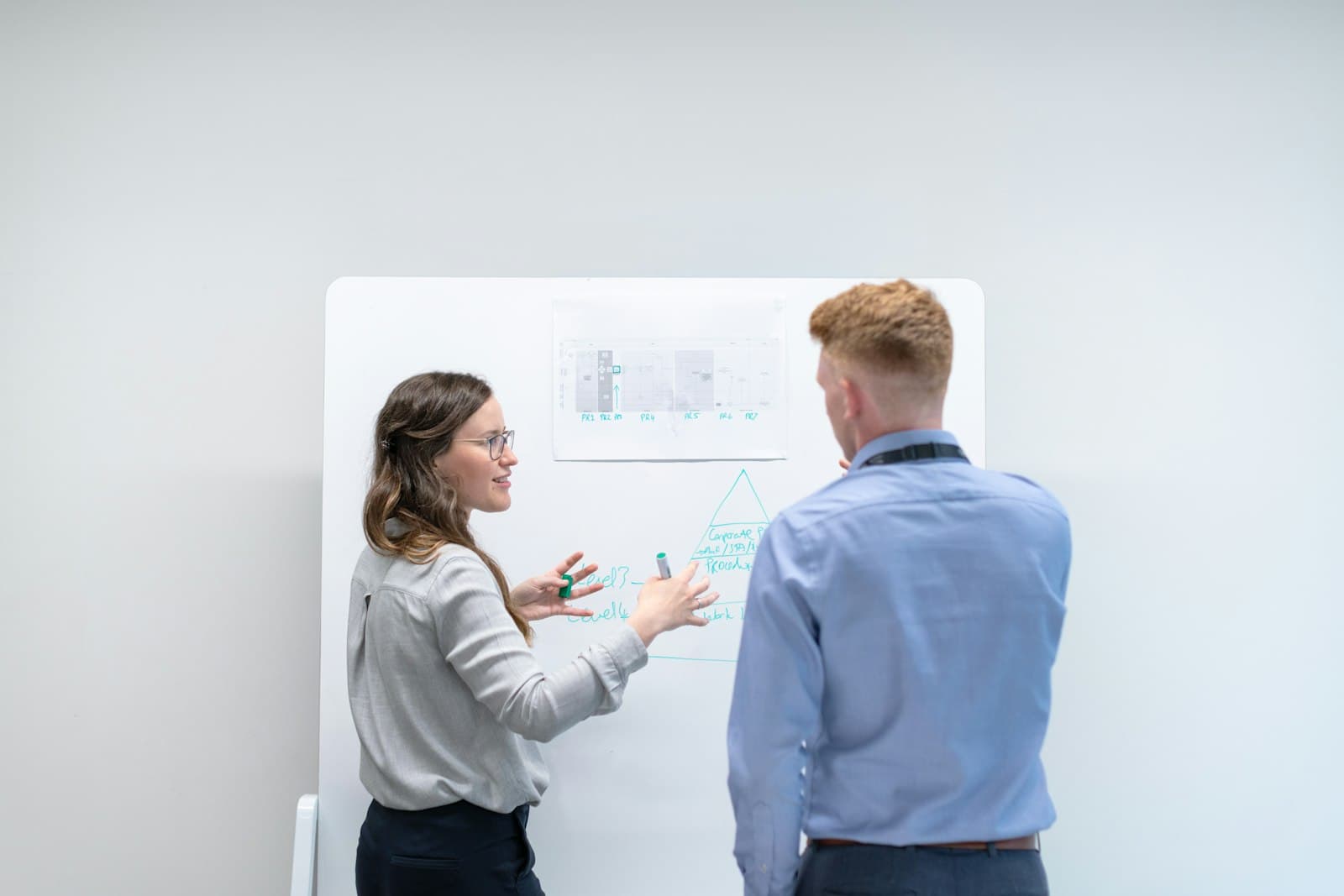 Two colleagues discussing ideas at a whiteboard