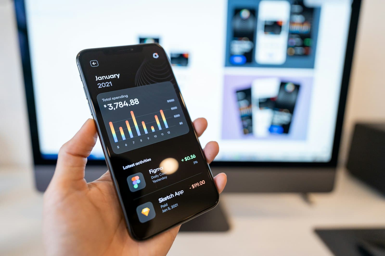 Hand holding a phone with a dark-mode analytics app